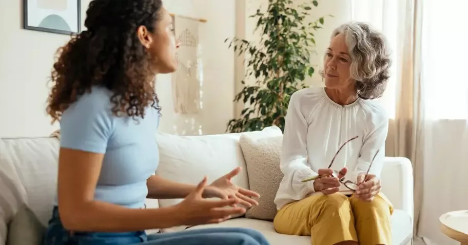 A practitioner having an honest, one-on-one conversation with a client in a warm, plant-filled room