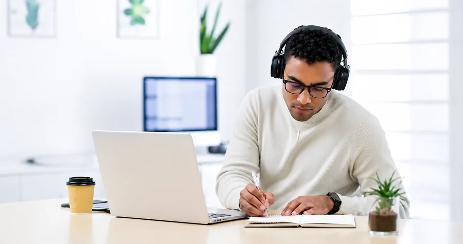 A practitioner taking notes on a call, preparing for a demo conversation at a plant-filled desk